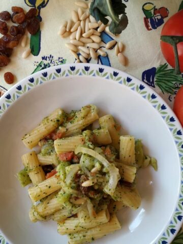 A close up from above of Broccoli Pasta on a white plate. The pasta shown broccoli and a few pine-nuts on top
