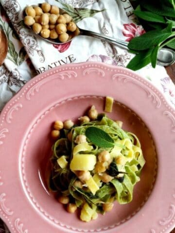 A view from above Chickpeas Tagliatelle in a pink dish. The dish is garnished with fresh sage and chickpeas.