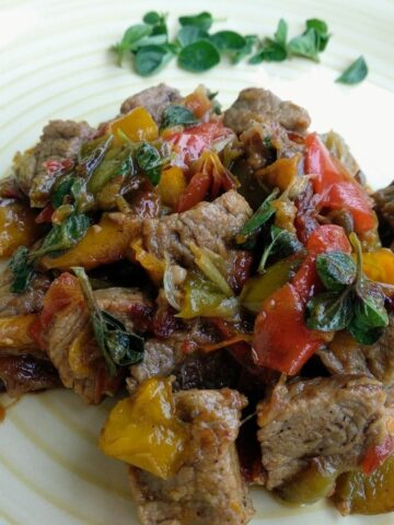 Peppers Beef Stew in a white plate. It is garnished with fresh herbs