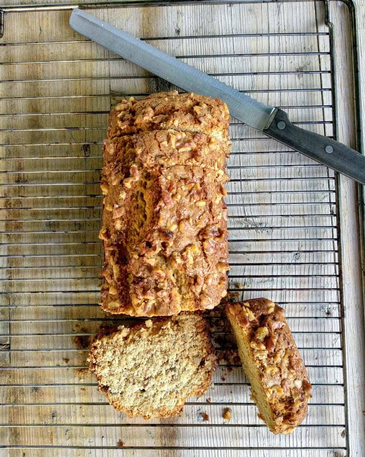 A-Banana Bread-Loaf-on-a tray on a ligh wood table. The loaf is sliced showing inside