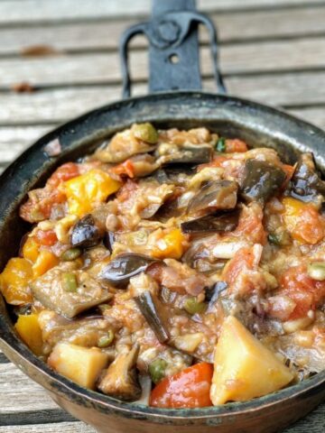 Italian Caponata in a copper pan on a wooden table