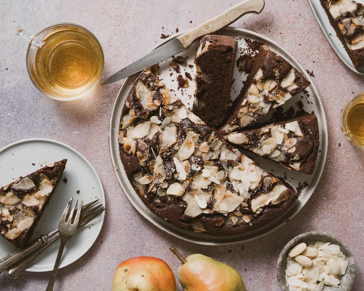 Sliced Chocolate and Pear Cake on a  rustic table. The slices shown the pears baked inside and almonds on top