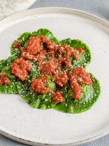 Spinach Ravioli with Pistachio view from above. Ravioli are dressed with tomato sauce