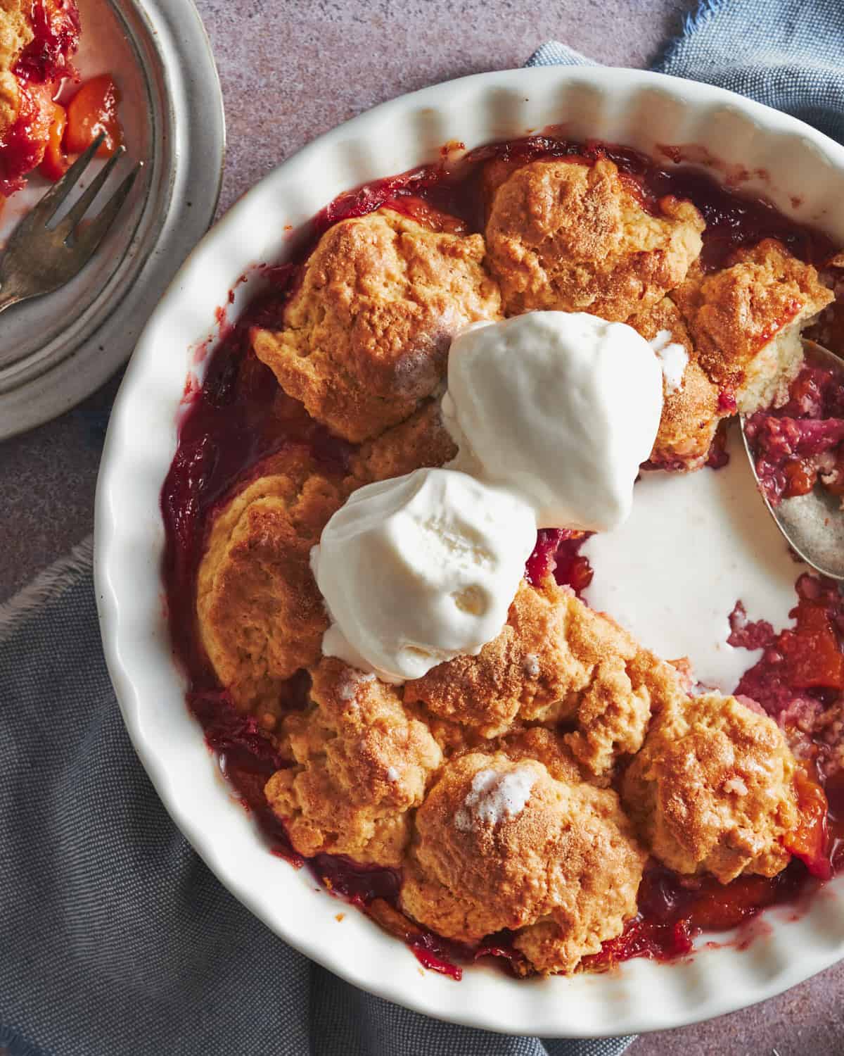 Peaches and Raspberries Cobbler in a baking tray. It shown all fruit baked inside. It is served with some ice-cream