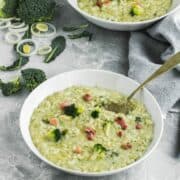Two plates with Broccoli Risotto with Gorgonzola in white plates. Risotto is topped with broccoli florets and pancetta