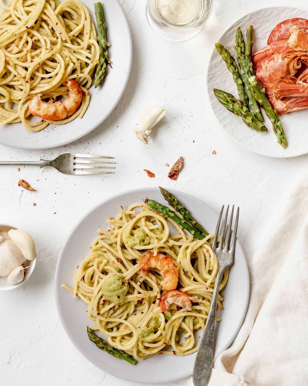 A view from above of 3 plates of Asparagus Spaghetti with Prawns. They are served with asparagus and prawns on top