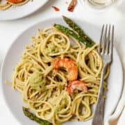 A view from above Asparagus Spaghetti with Prawns in a white dish with a fork. It is garnished with asparagus and prawns.