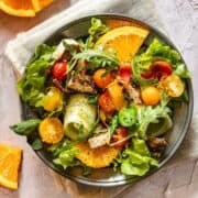 Bowl with Chicken salad from above. It combines Chicken with tomatoes, salad and orange slices