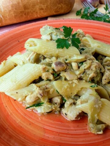 A close up of Artichockes and Mackerel Penne on a red plate