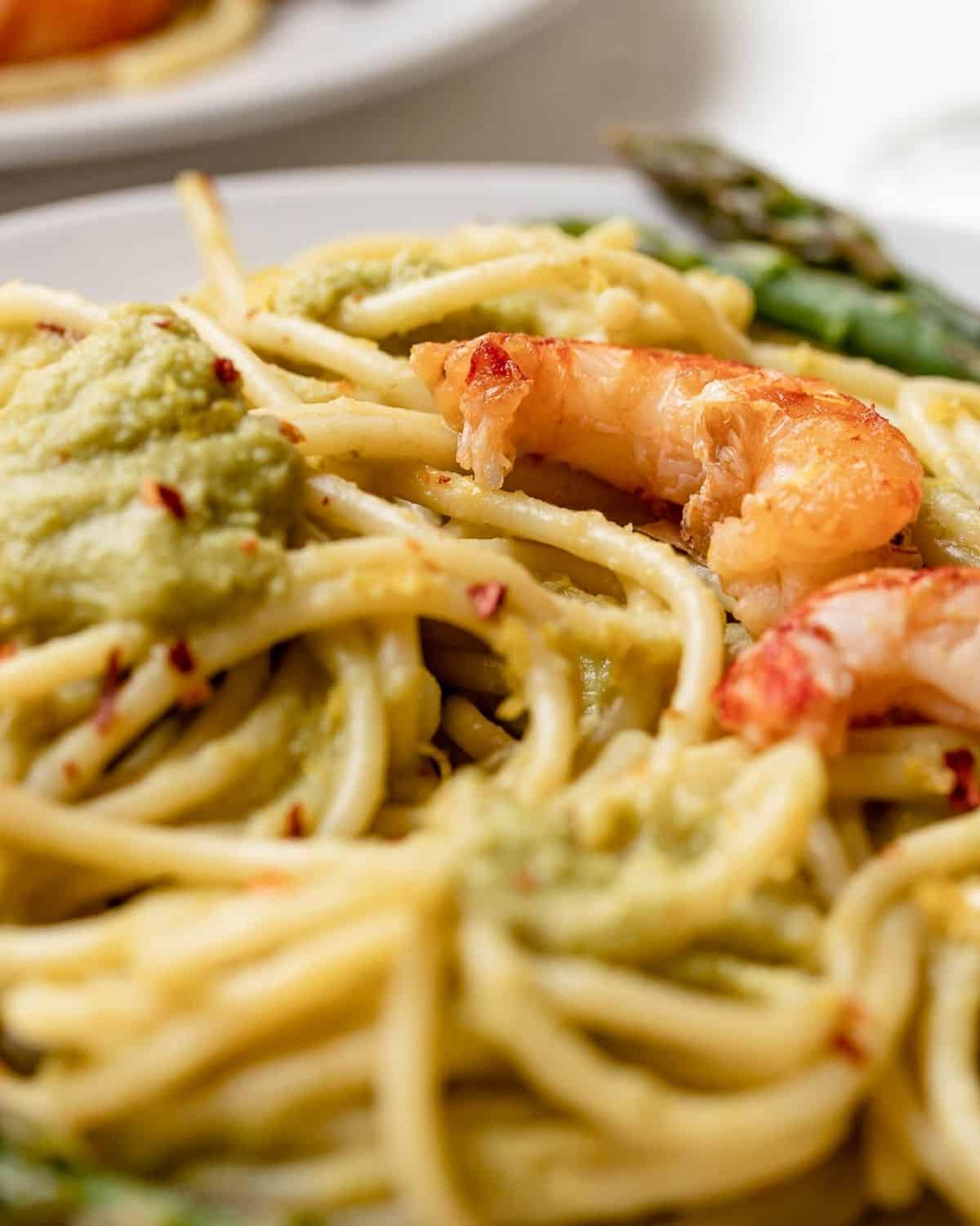 A close up of Asparagus Spaghetti showing a prawn on top