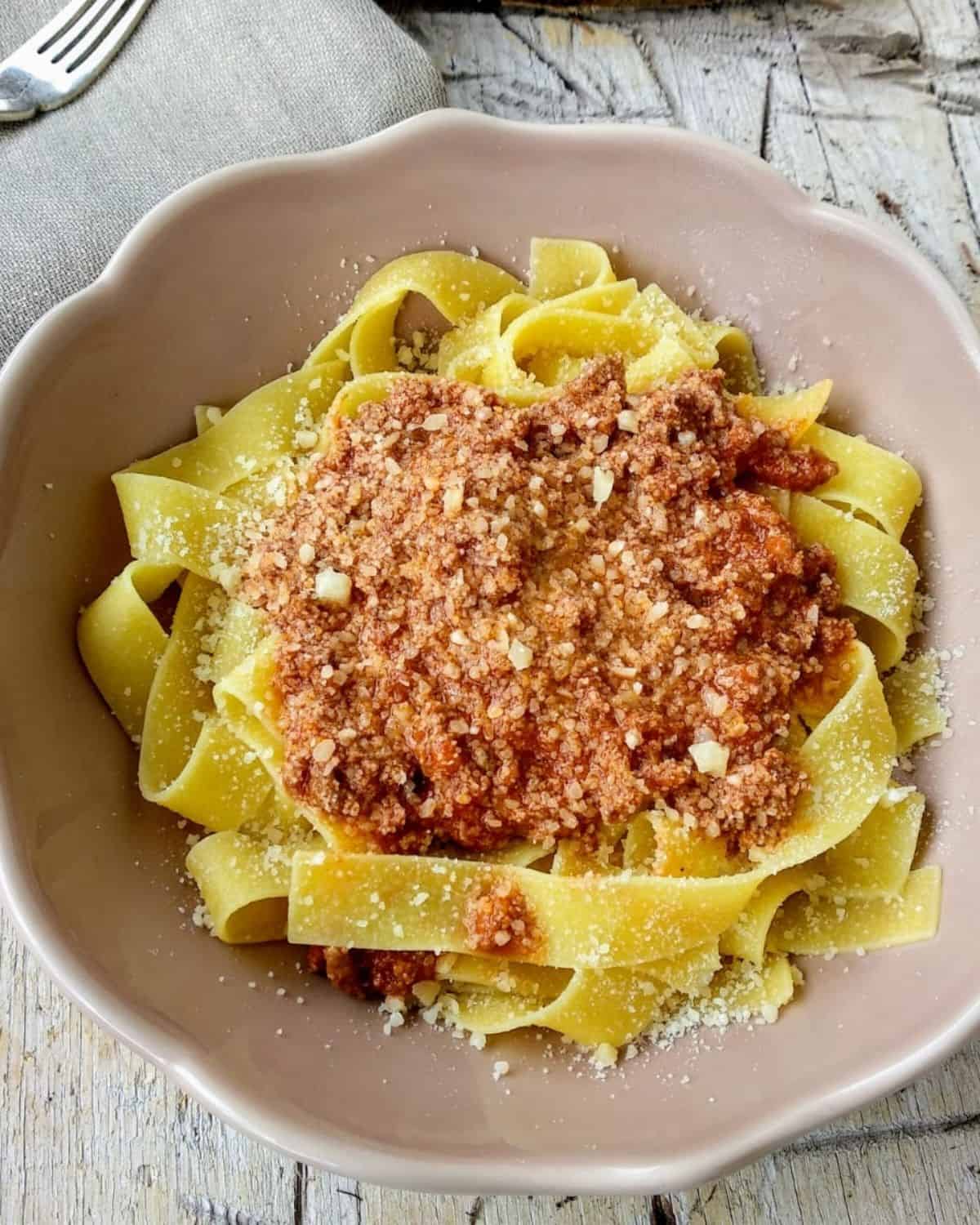 Italian Ragù Tagliatelle from above in a pink plate on a rustic wooden table