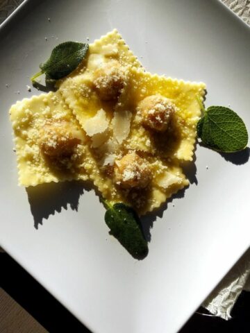 Pumpkin Ravioli from above showing grated parmesan and sage leaves on top