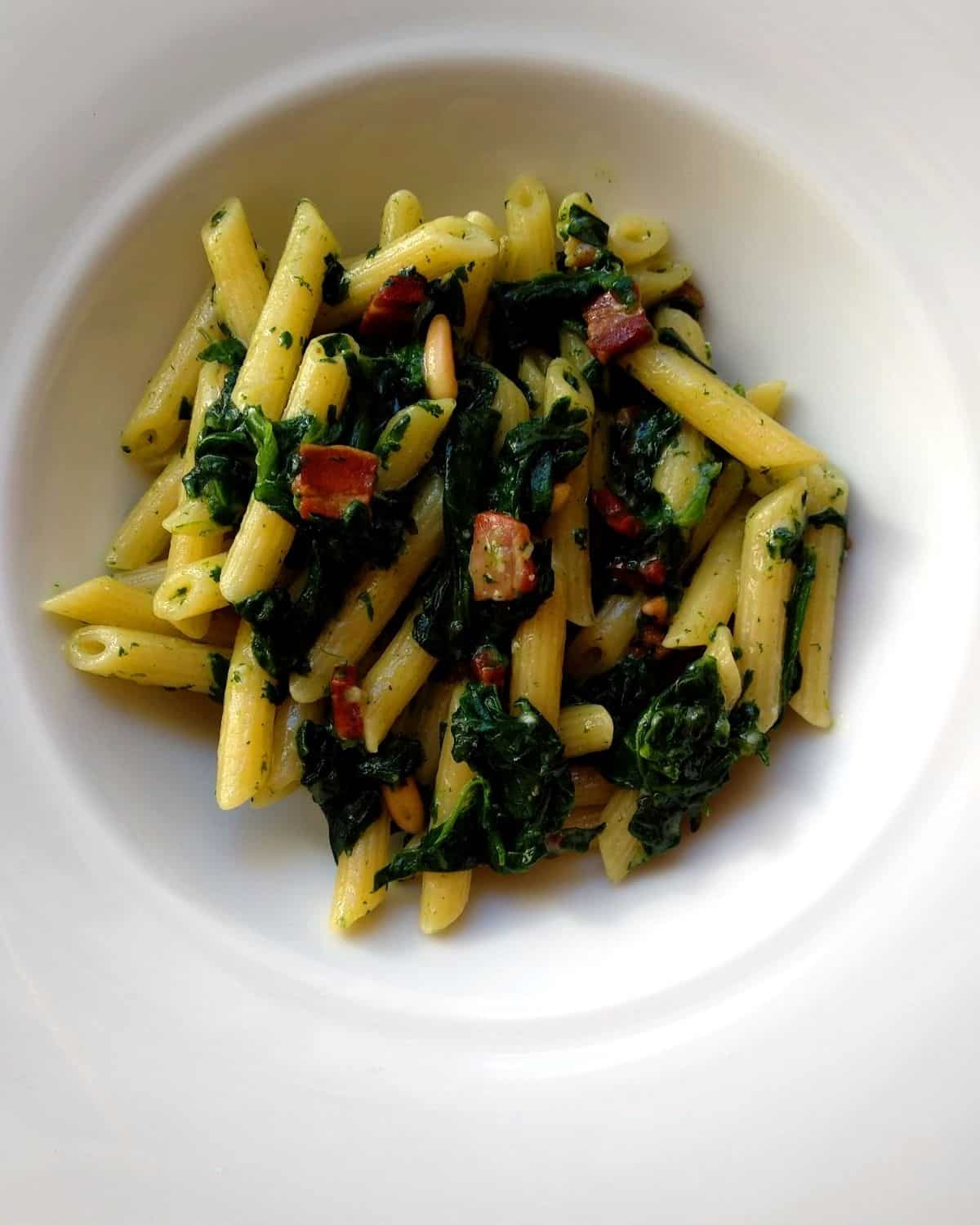Spinach Pennette with Italian Pancetta view from above in a white plate