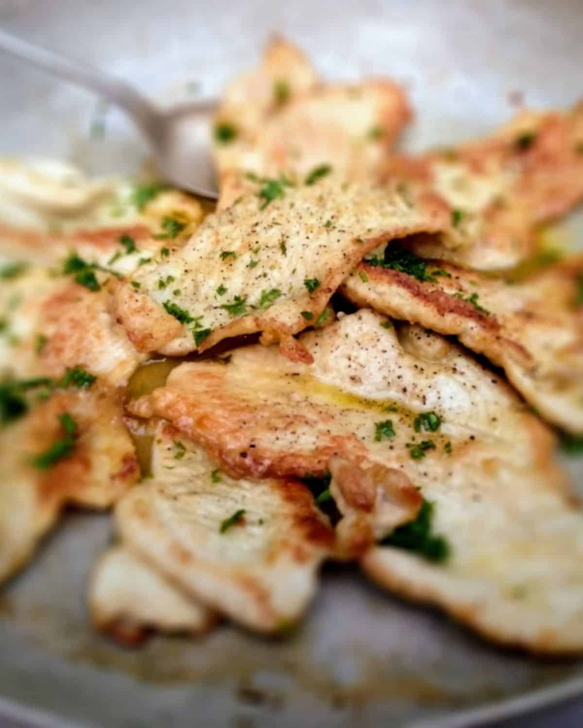 A close up from above of Chicken Breast slices with Juniper and Orange in a pan.
