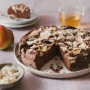 Two slices of Chocolate and Pear Cake on a grey rustic table. The slices shown the pears baked inside and almonds on top