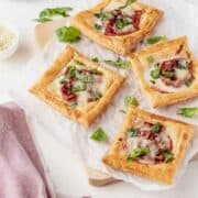 4 galettes on a board shown from above. They are show the mozzarella nad prosciutto filling. They are garnished with fresh basil leaves